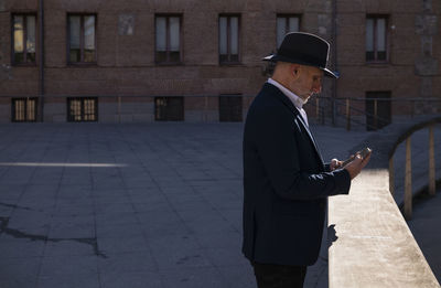 Side view of man standing against building