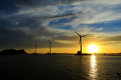 Silhouette wind turbine against sky during sunset