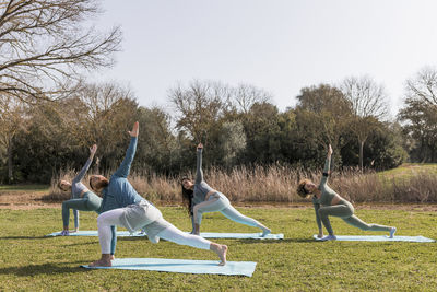 Male instructor exercising with female friends in public park