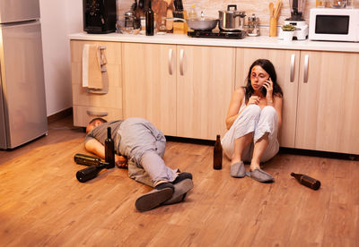 Side view of woman sitting on hardwood floor at home