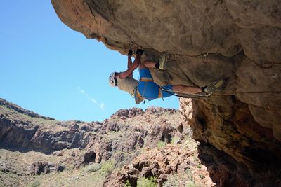 Low angle view of person standing on rock against mountain