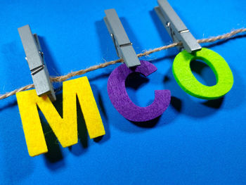 Close-up of multi colored clothespins on rope against blue background