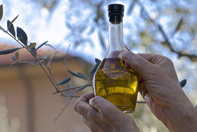 Midsection of person holding glass bottle