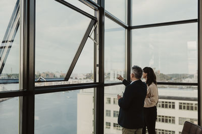 Businessman pointing while female colleague standing by in office