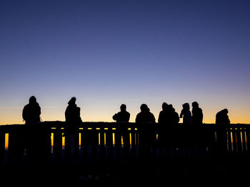 Silhouette people against clear sky during sunset