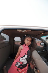 Portrait of happy girl on car against sky