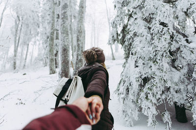 Rear view of woman leading man in the snow