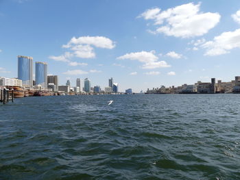 Sea by buildings against sky in city