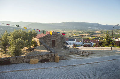 Road by buildings against clear sky