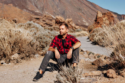 Man looking away while sitting on land