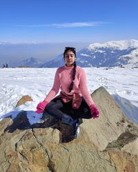 Woman sitting on snow covered mountain