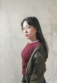 Portrait of beautiful young woman standing against wall