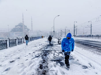 Rear view of man walking on snow covered landscape