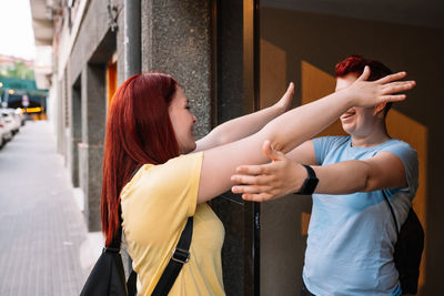 Happy friends embracing each other near building