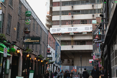 People walking on street amidst buildings in city