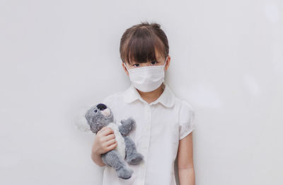 Full length portrait of girl standing against white background