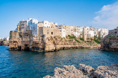 Buildings by sea against blue sky