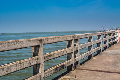 Pier over sea against clear blue sky