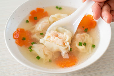 Cropped hand holding food in bowl on table