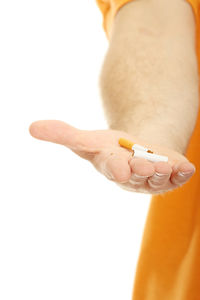 Close-up of hand holding cigarette against white background