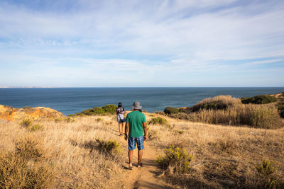 Rear view of friends on sea shore against sky