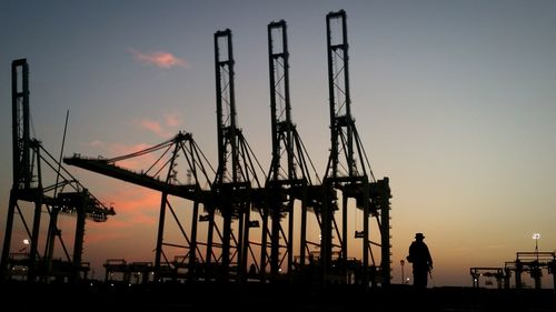 Silhouette of man at harbor against sky during sunset