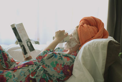 Low section of woman resting on bed at home