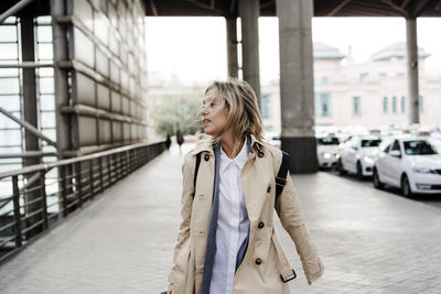 Woman wearing long coat walking on sidewalk at train station