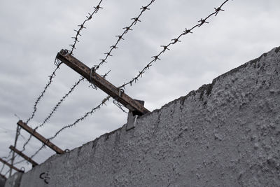 Low angle view of barbed wire against sky