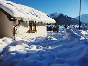 Snow covered land and houses against sky