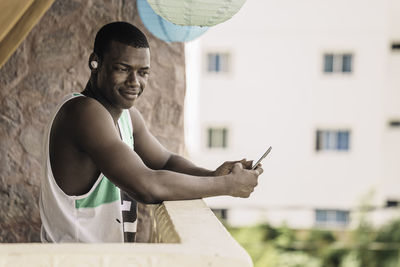 African american tourist listening to music and smiling with cellphone in hands