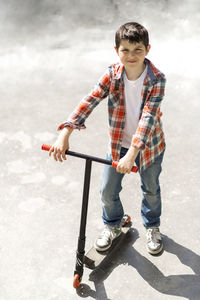 Boy playing with push scooter on street