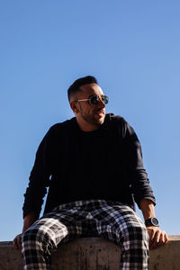 Low angle view of man sitting against sky