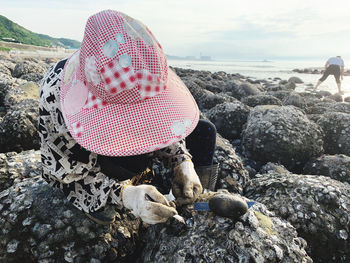 Close-up of hat on rock at beach against sky