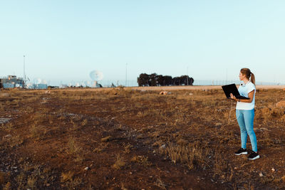 Woman standing on field against clear sky