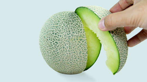 Close-up of hand holding fruit over white background