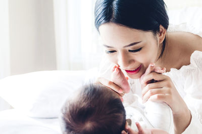 Close-up of smiling mother playing with son on bed at home