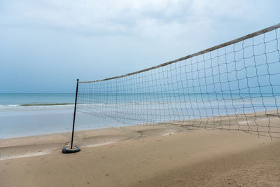 Volleyball net at sea shore against sky