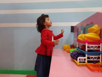 Side view of a girl standing against wall