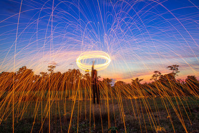 Light trails on field against sky