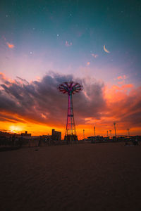 Silhouette built structure on beach against sky during sunset