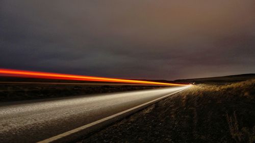 Light trails on road against sky at night