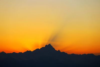 Scenic view of silhouette mountains against orange sky