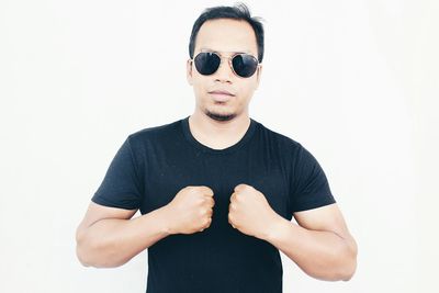 Portrait of young man wearing sunglasses against white background