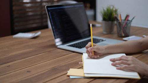 Midsection of person using smart phone on table