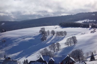 Scenic view of snow covered mountains against cloudy sky