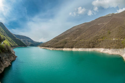 Scenic view of lake by mountains against sky