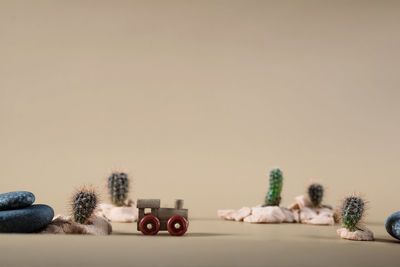 Background image of wooden toy steam locomotive in desert with stones and cactuses on beige backdrop