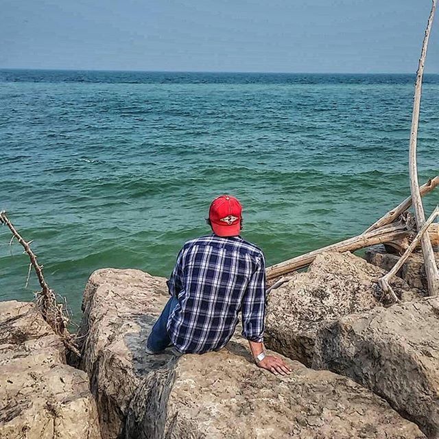 rear view, water, lifestyles, leisure activity, full length, sea, standing, casual clothing, men, person, tranquil scene, tranquility, sitting, beauty in nature, scenics, nature, horizon over water, rock - object