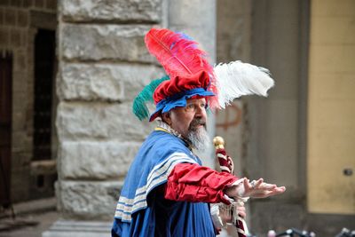 Side view of person with umbrella standing against building